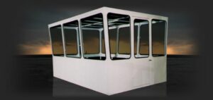a white control cab built by cabs rops and attachments with 12 large windows, 3 on each side of the cab, on a dark sunset sky background