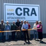 Several people gather in front of a building marked with a sign that says "CRA," showcasing a ribbon cutting ceremony with community